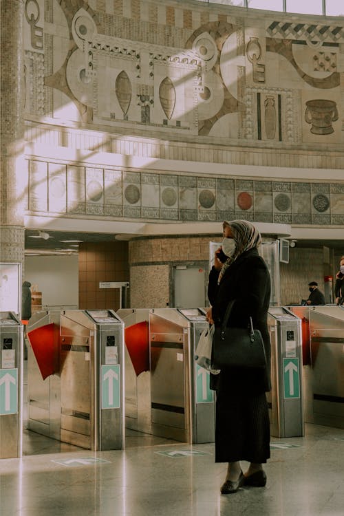 A Woman with Headscarf Wearing Face Mask while Standing on a Train Station