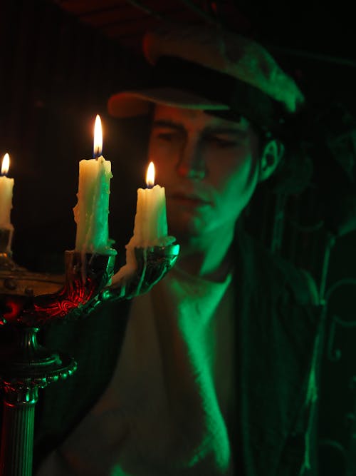 Photo of a Man Looking at Lit Candles