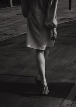 Black and white photo of a woman walking in high heels on a street.