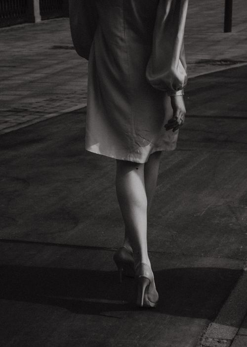 Free Black and white photo of a woman walking in high heels on a street. Stock Photo