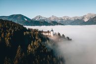White Concrete Building Near Green Trees and Mountain