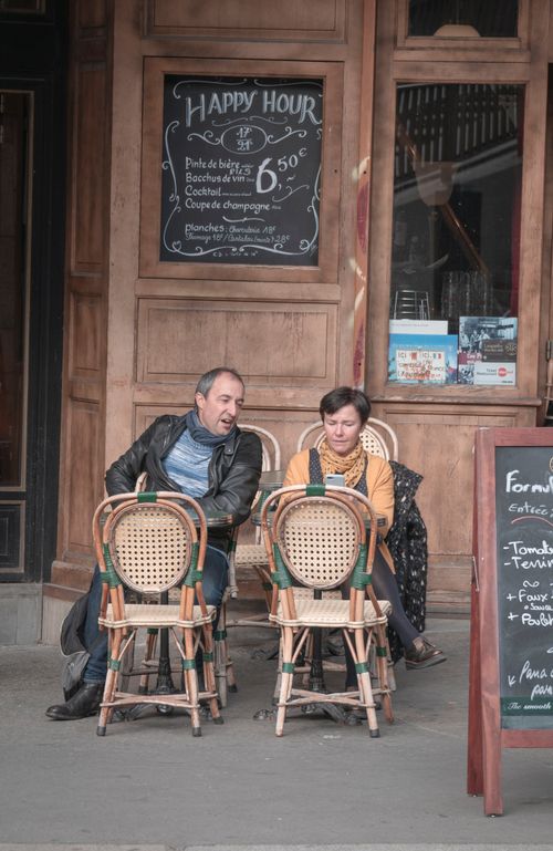Free A lively Parisian cafe with patrons enjoying outdoor seating in a bustling urban setting. Stock Photo
