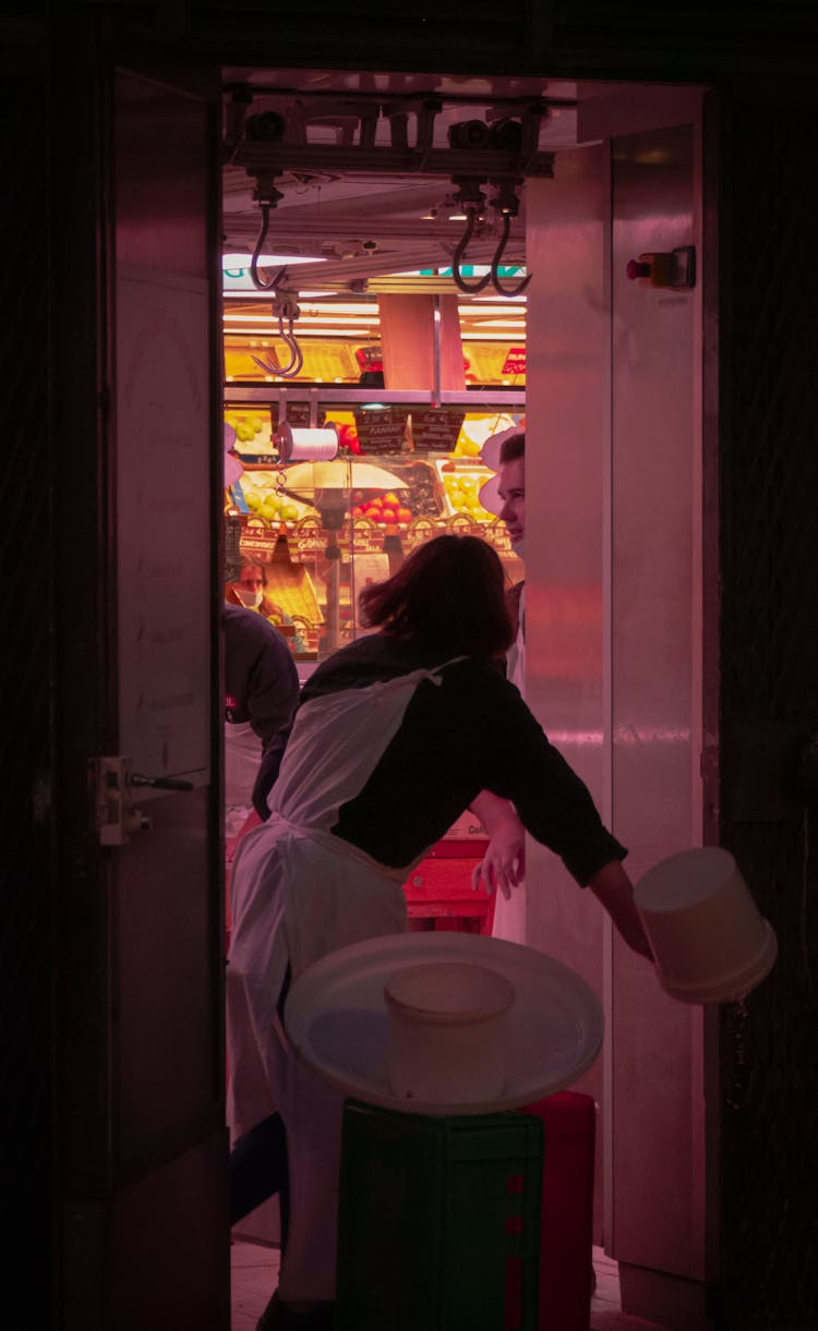 Worker Emptying Bucket At Back Of Restaurant