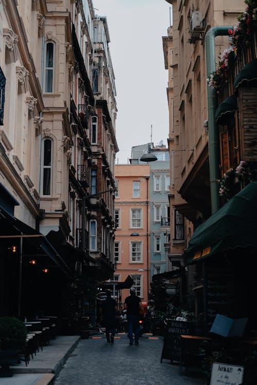 People Walking on the Street Between Buildings