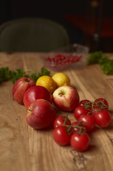 A selection of fresh apples, lemons, and cherry tomatoes on a wooden table, showcasing farm freshness.