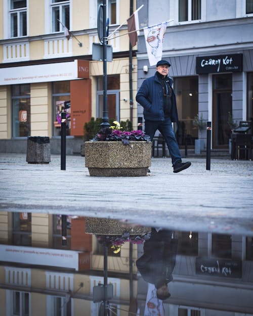 An Elderly Man Walking on the Street Side Near Buildings