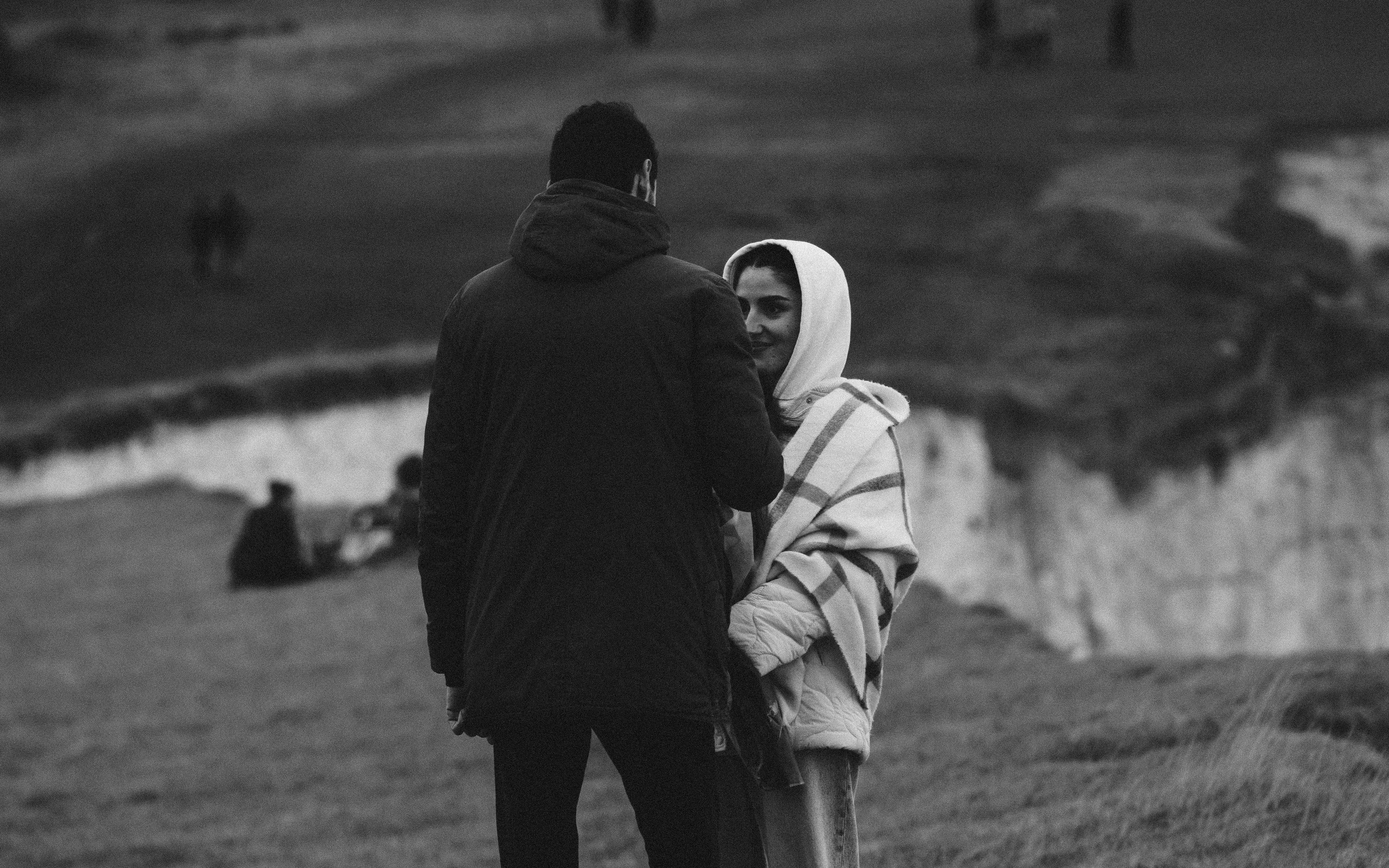 A black and white photo of a couple standing near cliffs in England's countryside.