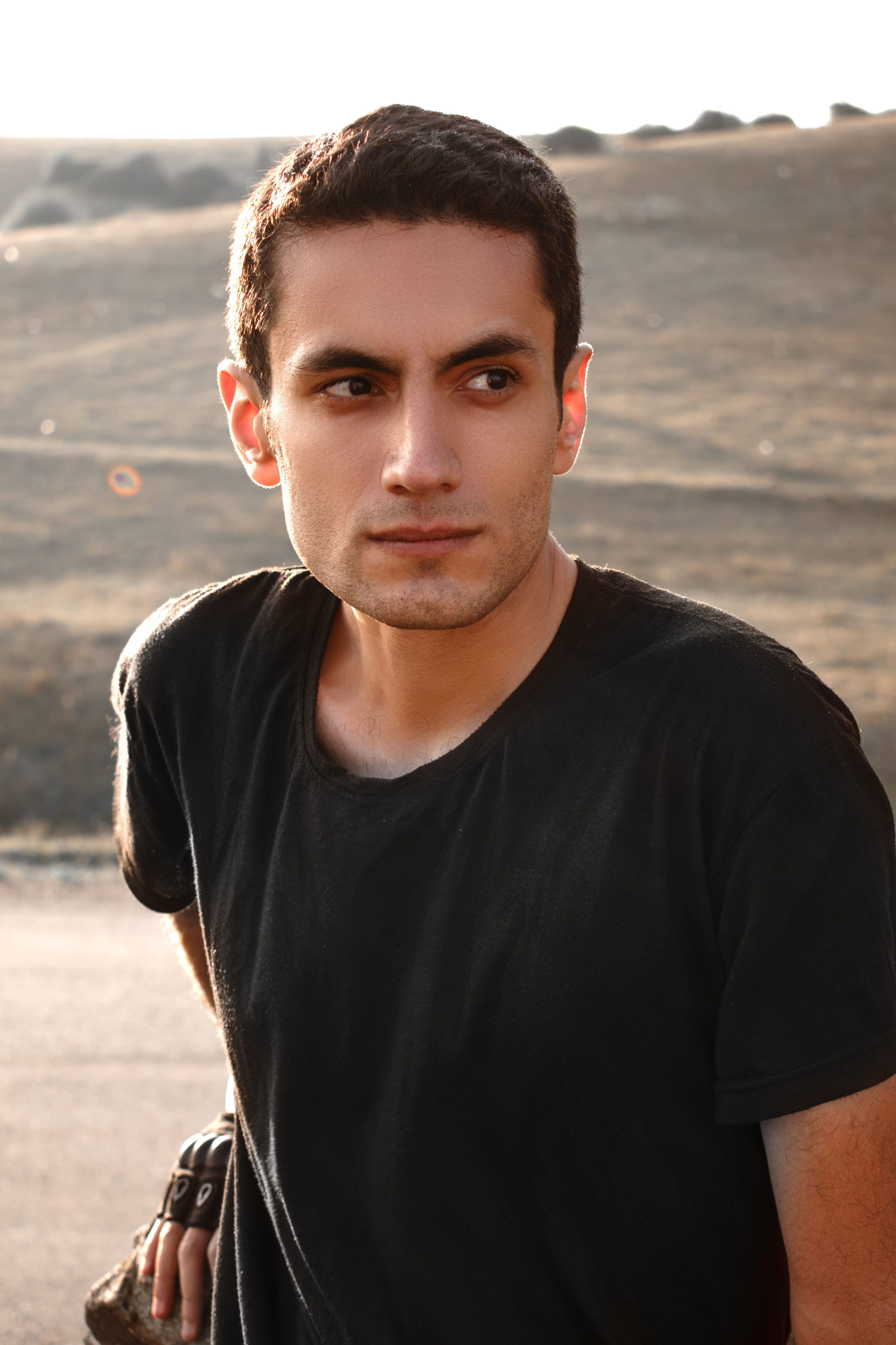 Portrait of a young man looking away in a serene outdoor environment.