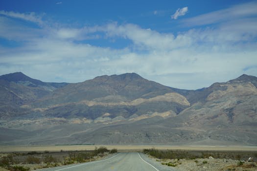 Vast mountain landscape in Death Valley National Park with a deserted road stretching into the distance.