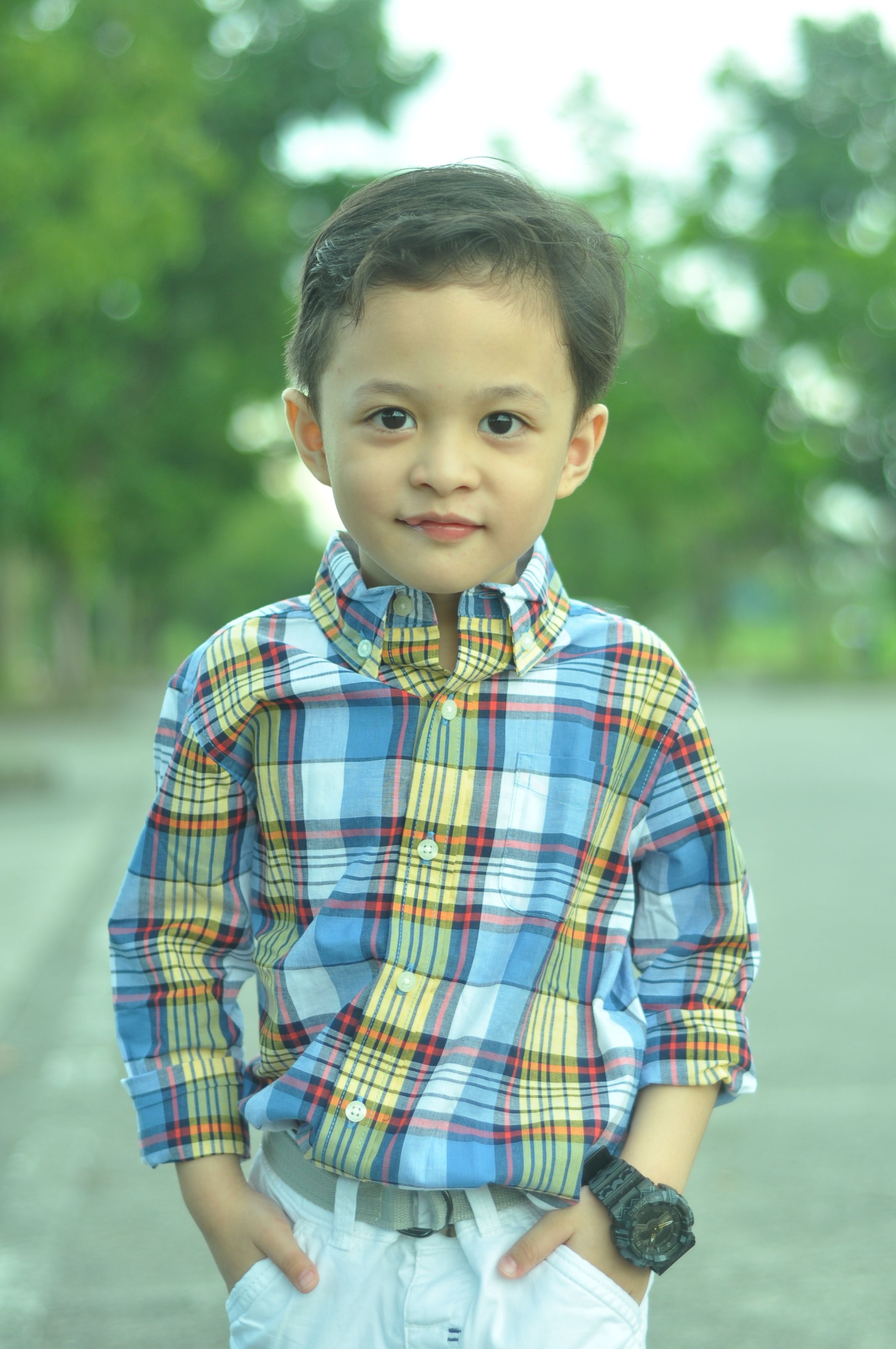 Charming young boy in a plaid shirt, smiling outdoors in the Philippines.