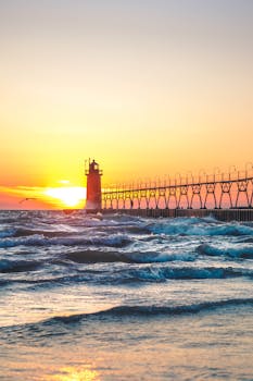 宁静的日落下，灯塔矗立在色彩斑斓、波浪温柔的海洋中