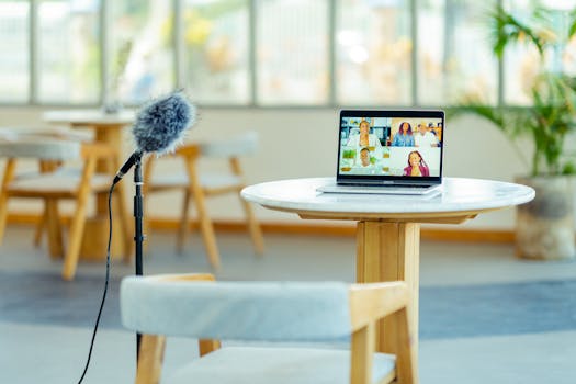 A cozy podcast setup with a laptop and microphone in a modern interior setting.