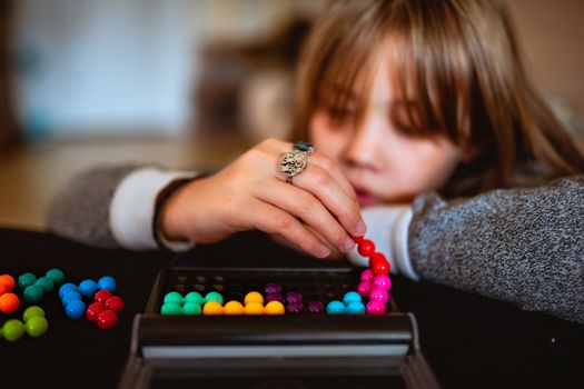 A young girl focused on assembling colorful beads in a puzzle game, showcasing concentration and creativity.