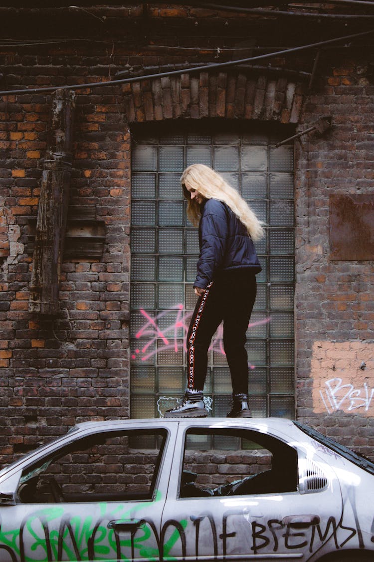 Woman With Long Blonde Hair Standing On A Car Roof
