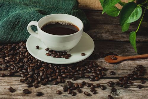 Free Warm rustic scene of a coffee cup on wooden table with scattered beans. Stock Photo