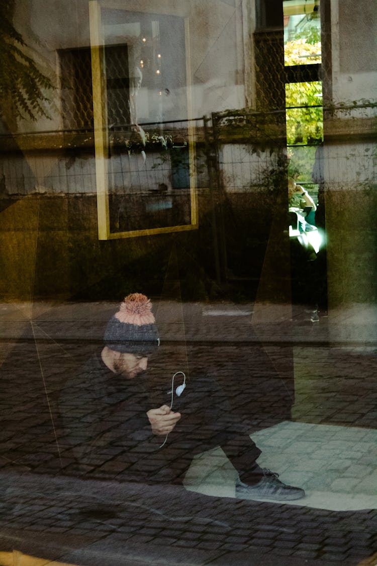 Window Reflection Of A Man Sitting On The Floor 