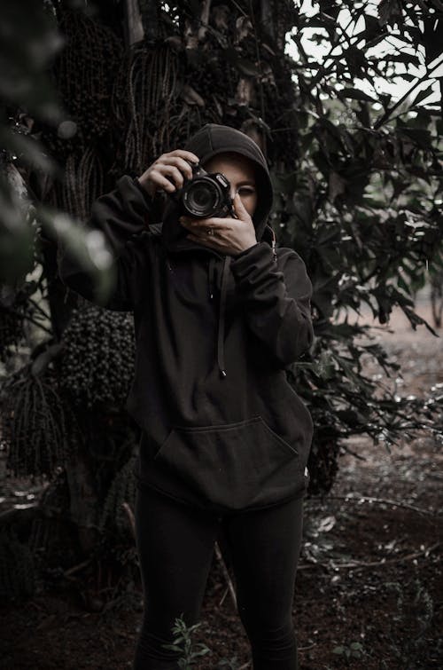 Woman Wearing Hoodie Taking Photo with a Camera
