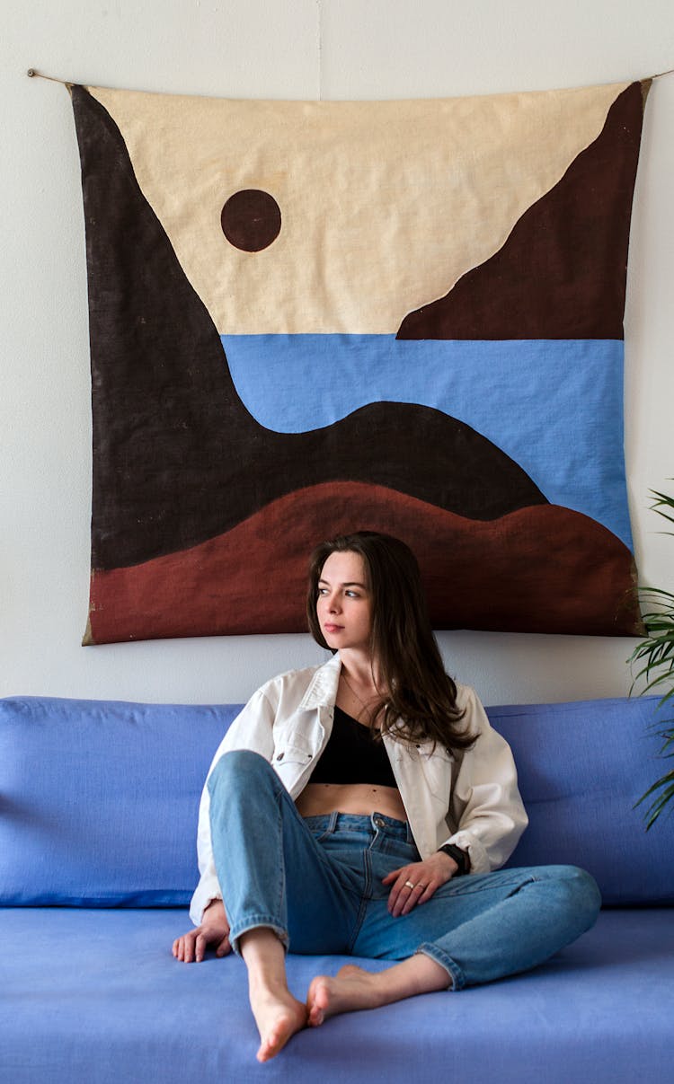 Woman In Jeans Sitting On Blue Sofa