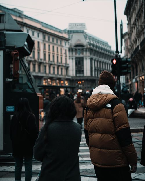 Free A vibrant group of people crossing a street in Milan, showcasing urban life amidst historic architecture. Stock Photo
