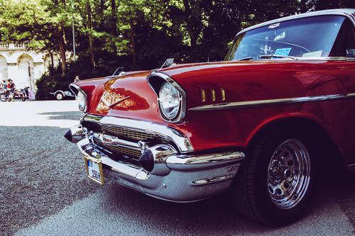 Free Close-up of a classic red vintage car with chrome details parked outdoors in sunlight. Stock Photo