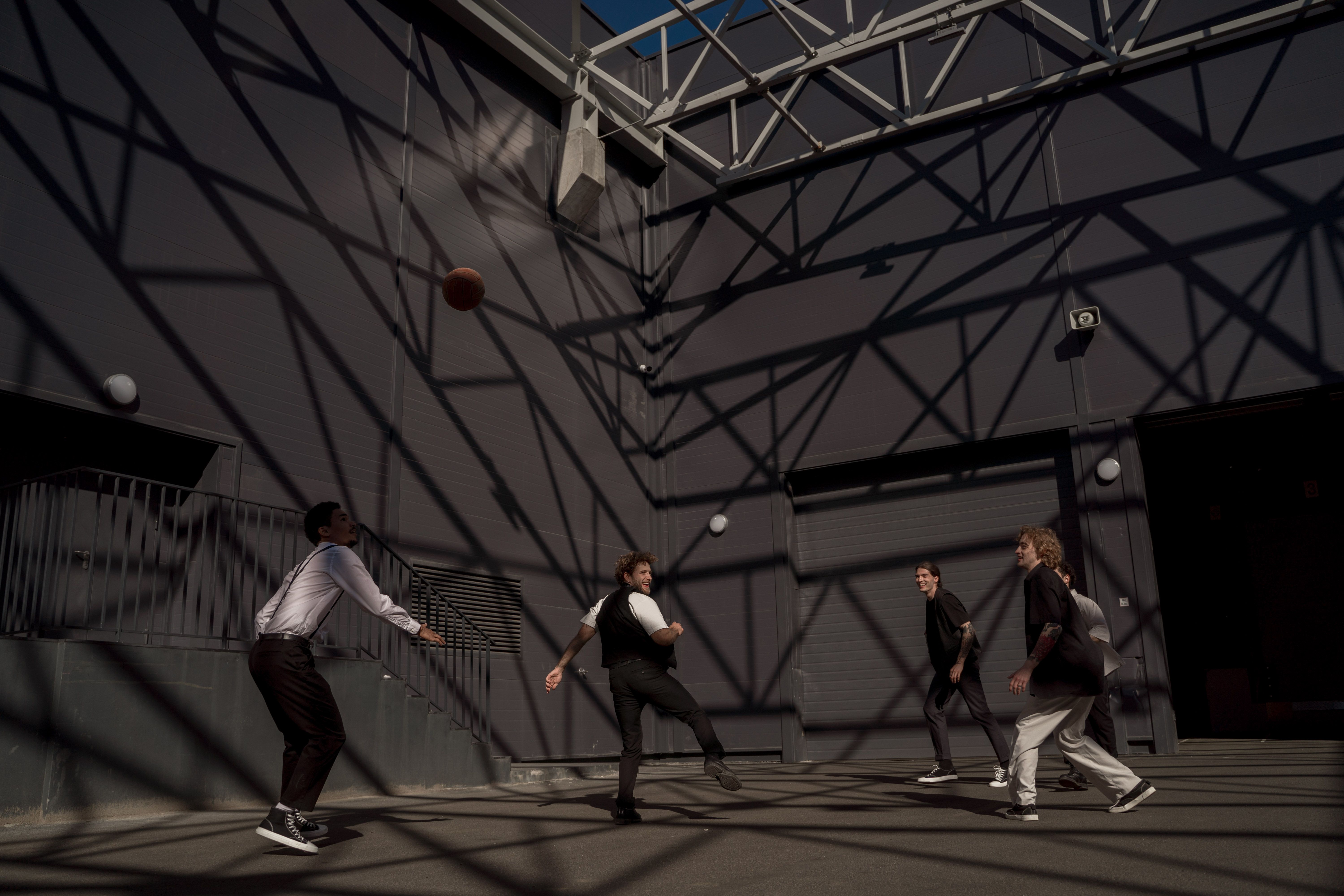 NBA photo featuring Four men playing basketball under crisscrossing shadows creating a dynamic urban setting.