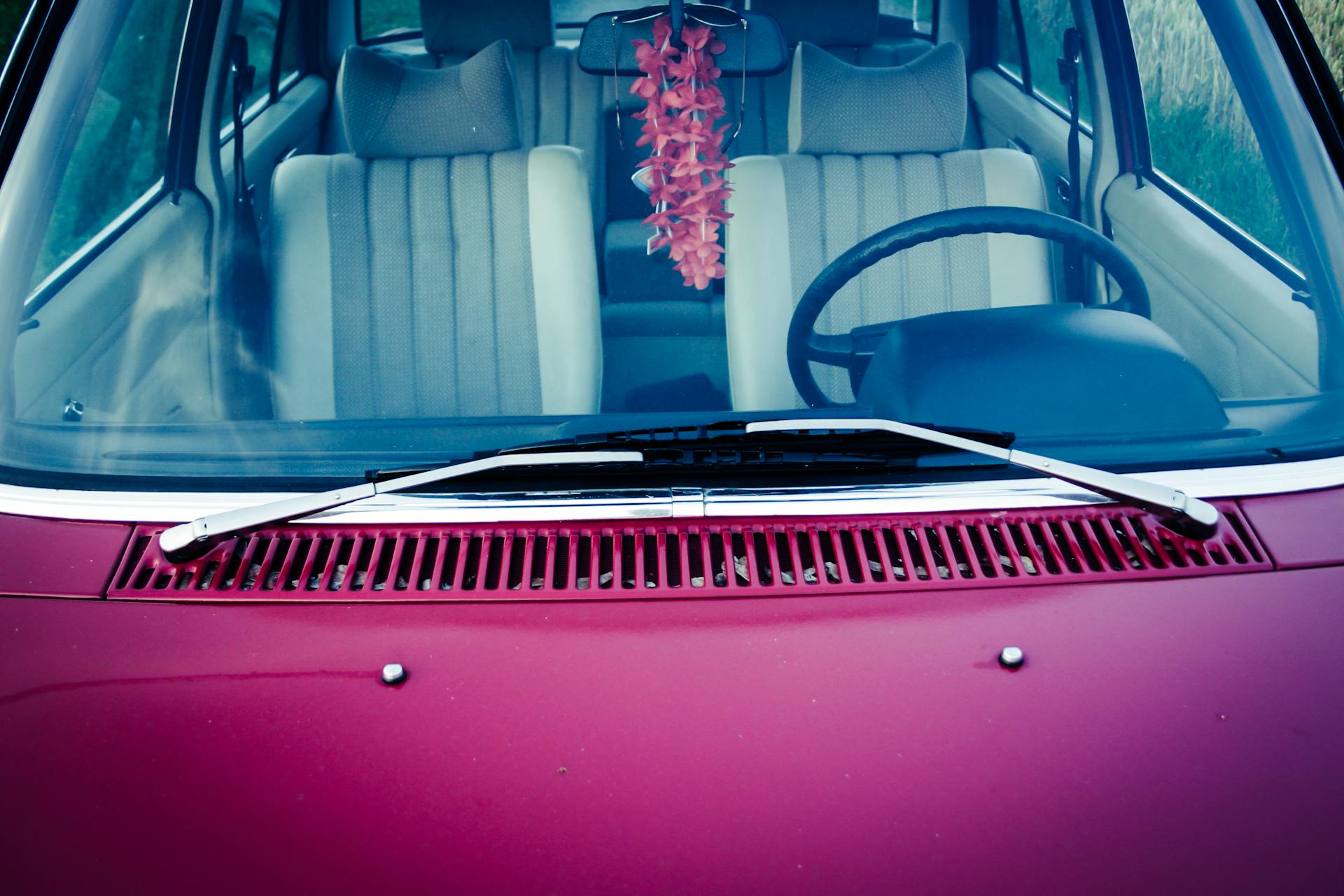 Explore the classic aesthetic of a vintage car interior through the windshield with a charming floral decoration.