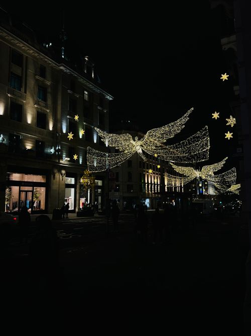 Free Magical Christmas lights featuring angels adorn Regent Street in London, creating a festive nighttime atmosphere. Stock Photo