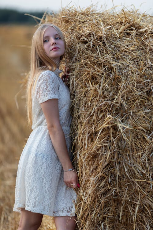Free A Young Woman in White Dress Standing on Brown Grass Stock Photo