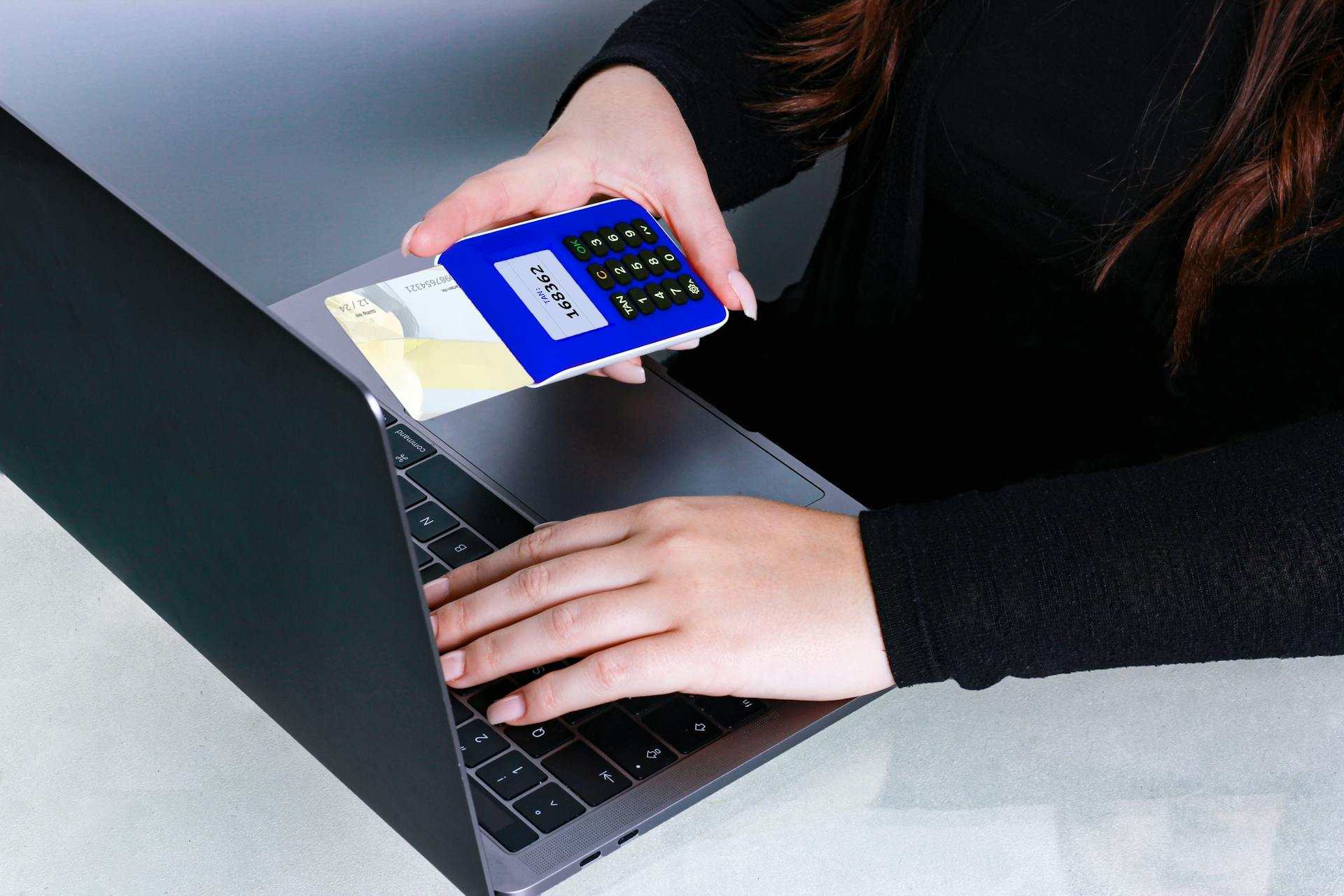 Person using card reader and laptop for secure online payment, showcasing modern cashless technology.