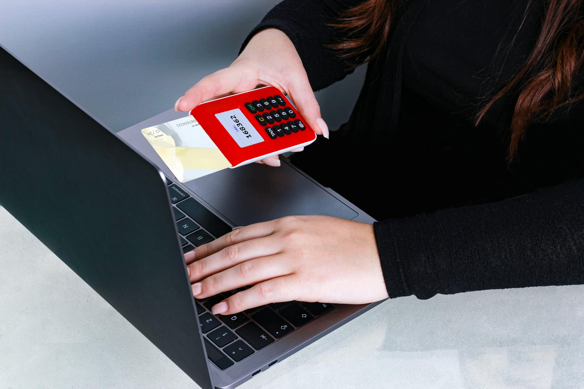 Close-up of hands using a credit card and laptop for online payment at a desk.