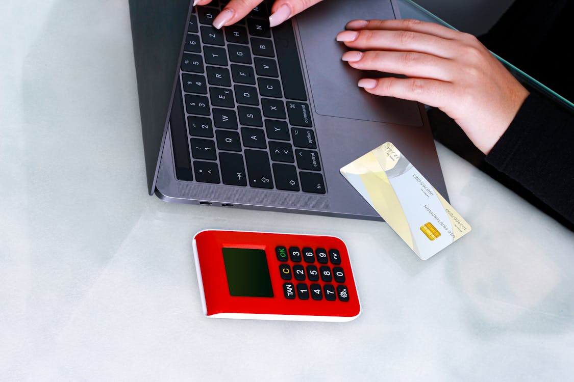 Free Hands using laptop with credit card and security device for online payment, emphasizing cybersecurity. Stock Photo