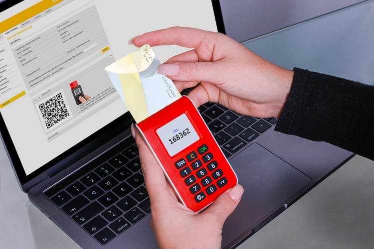 A Hand Holding Red POS Device With Visa Card