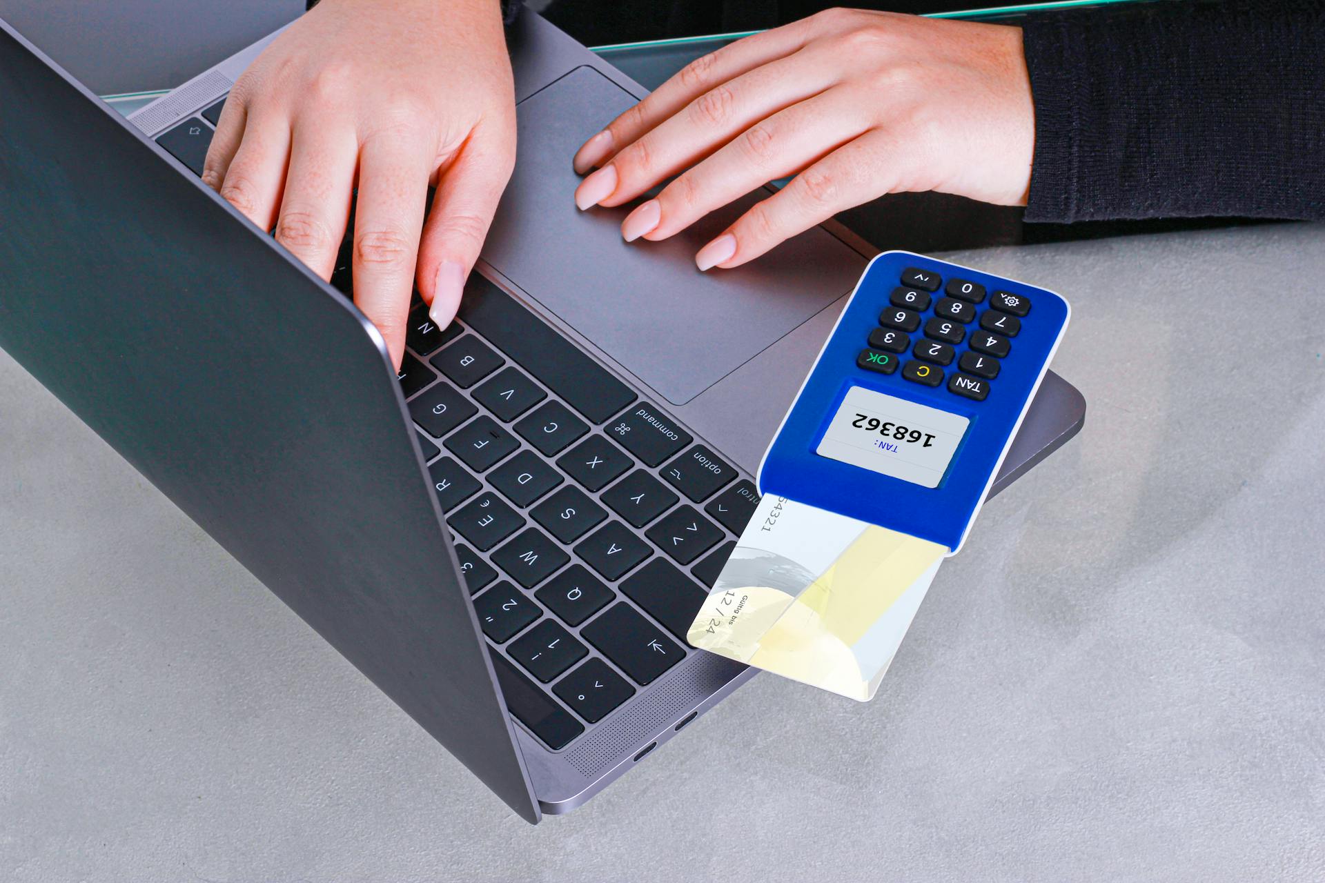 Person making an online payment using a laptop and card reader.