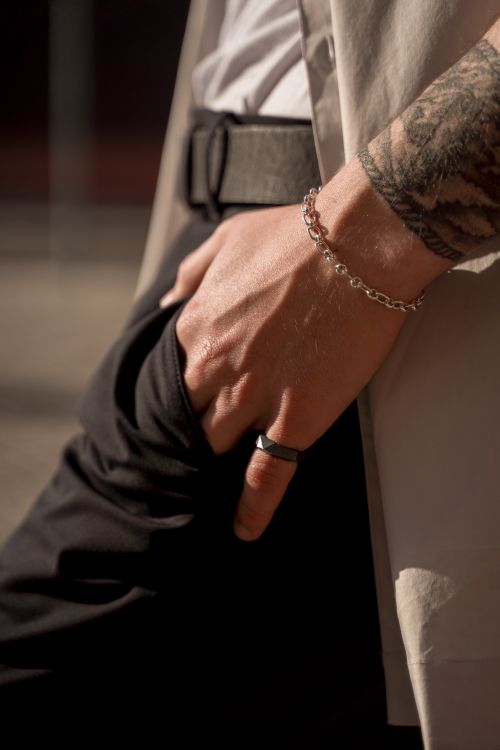 Free Close-up of a man's hand showcasing fashion accessories like a bracelet, ring, and tattoo under stylish lighting. Stock Photo