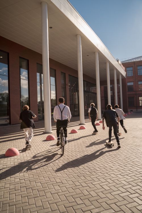 Free Dynamic scene of skateboarders and a cyclist on a sunny day near a modern building. Stock Photo
