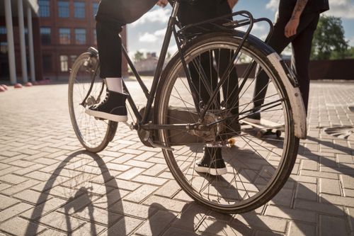 Free Urban scene with bicycle wheel and skateboarders in sunny weather, perfect for lifestyle themes. Stock Photo