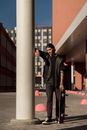 Man in Black Leather Jacket Standing Beside White Concrete Post