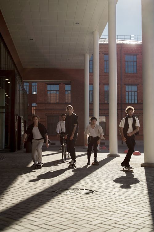 Free Five skaters enjoy skateboarding under a modern urban structure in daylight. Stock Photo