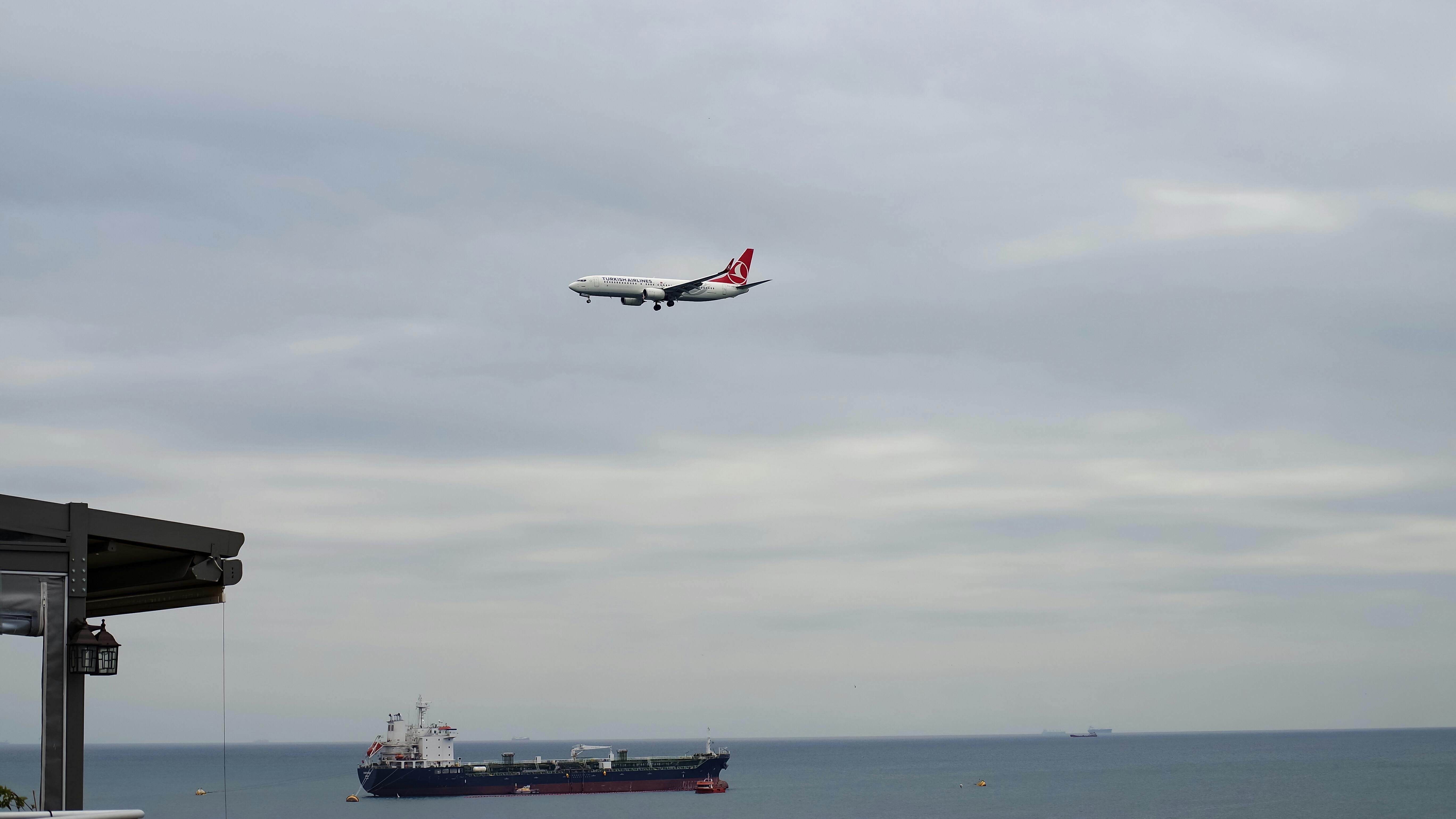 white plane flying above black ship