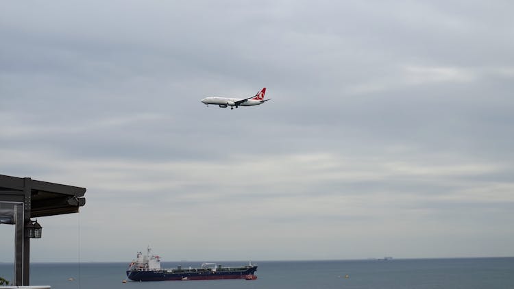 White Plane Flying Above Black Ship