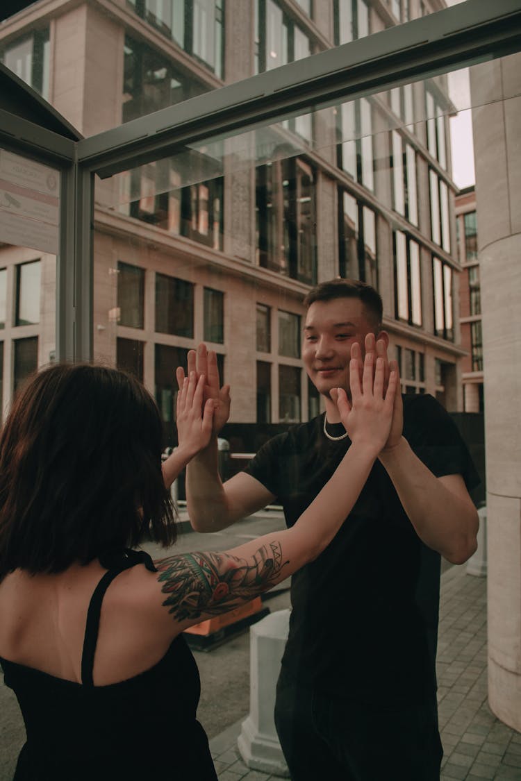 Woman And Man Touching Window Together