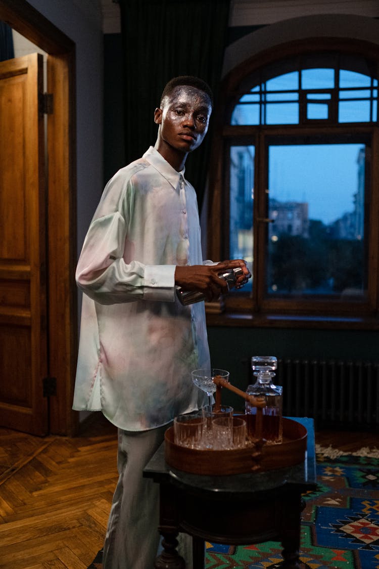 Portrait Of Young Man Making Cocktail By Window At Night