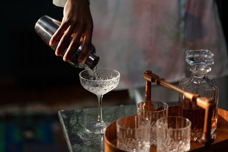 Hand Pouring Cocktail Into Glass From Shaker