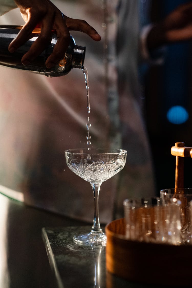 Close-up Of Hand Pouring Drink From Cocktail Shaker Into Glass