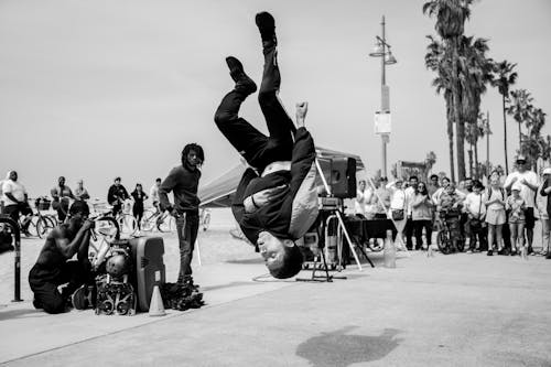 Grayscale Photo of Man Doing Backflip on the Street