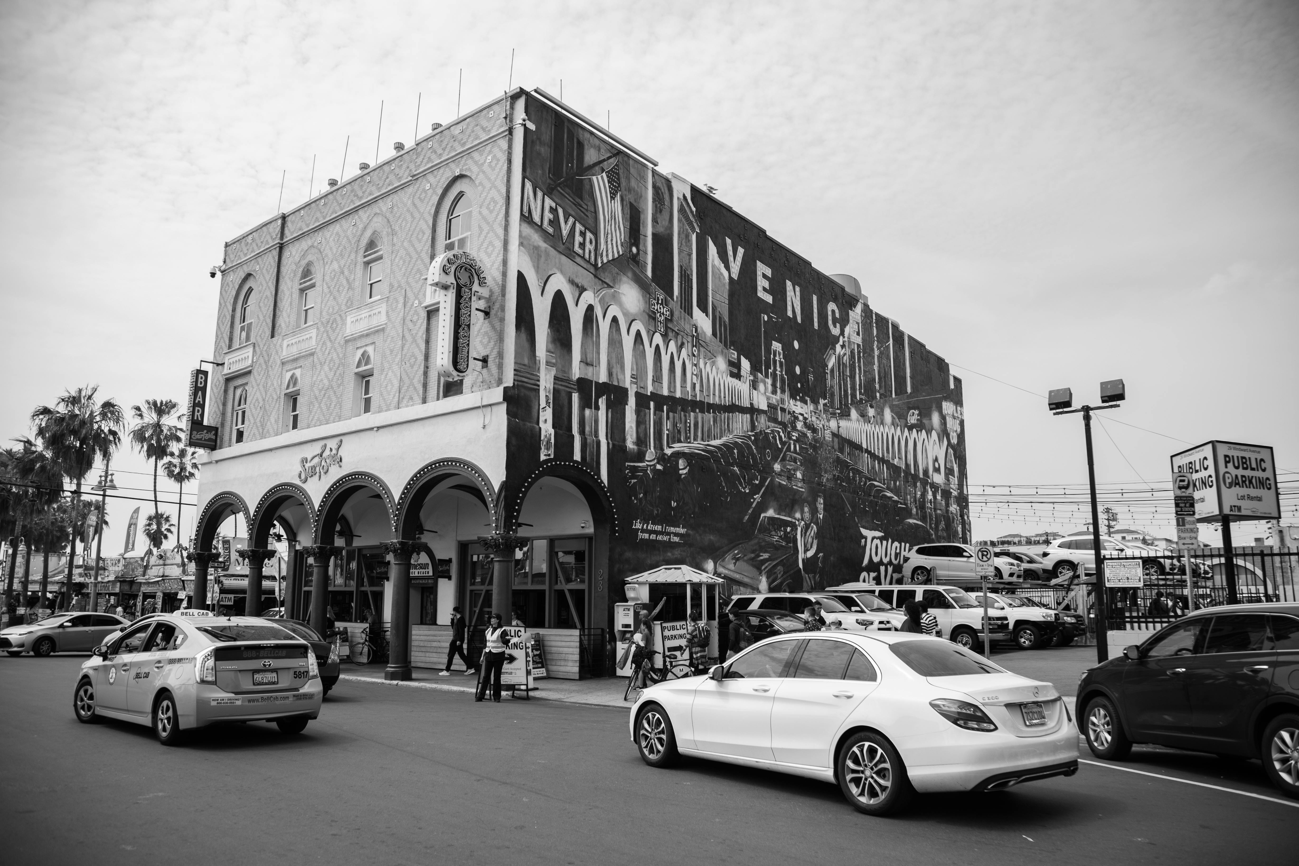 Grayscale photo of Venice Beach building with mural and cars in Los Angeles, CA.