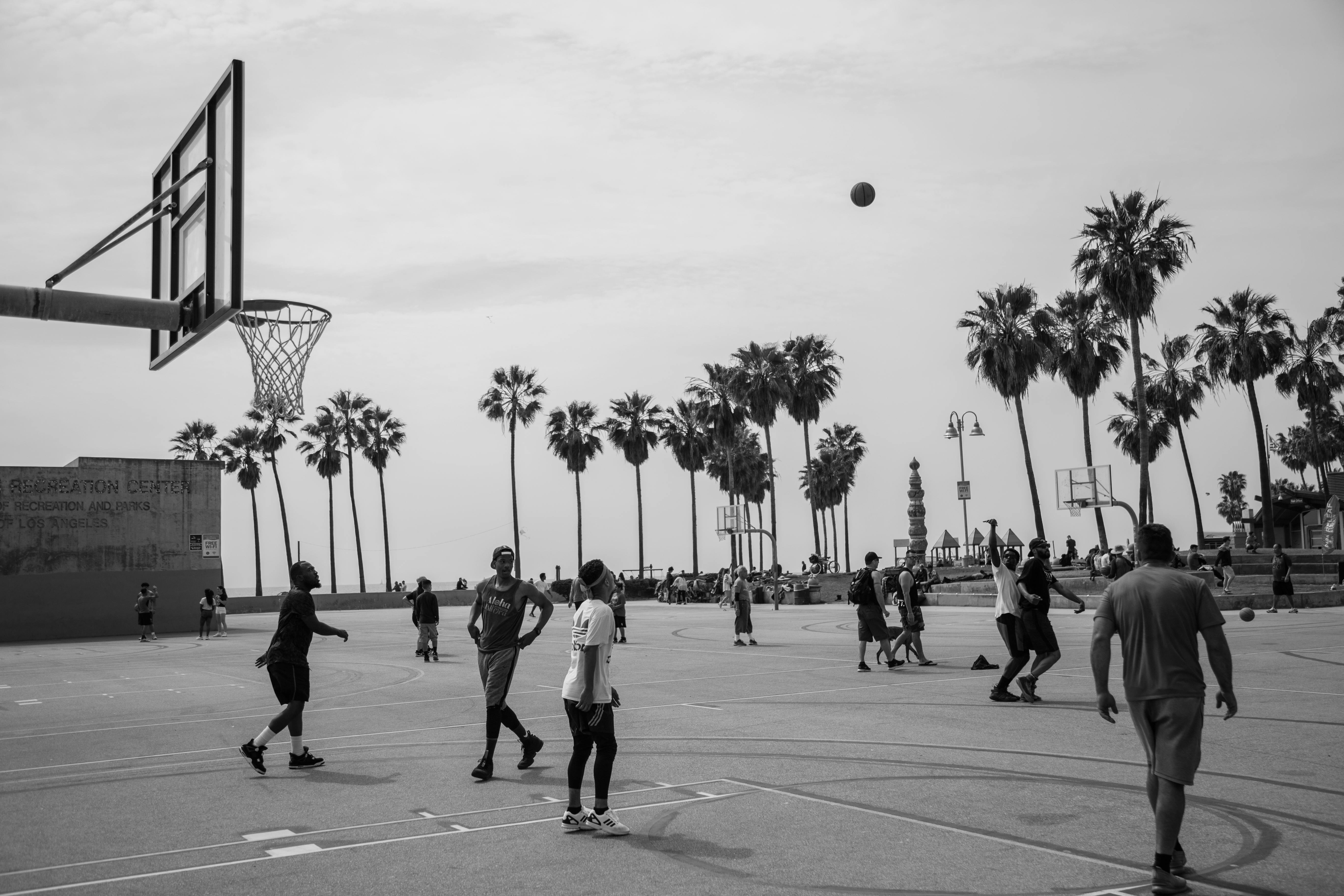 Black and white photo of a lively basketball game at Venice Beach, Los Angeles.