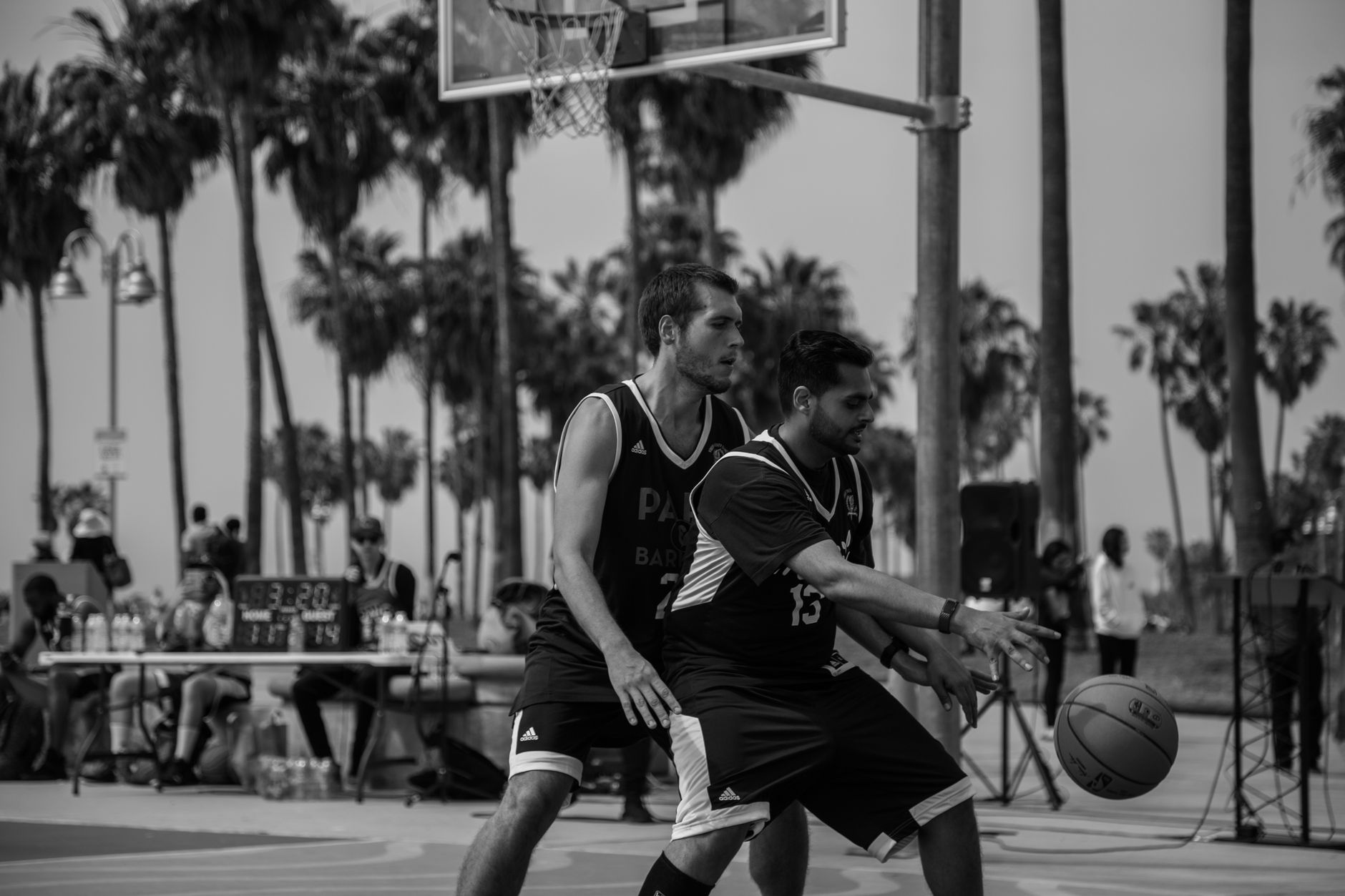 Black and white photo of men playing basketball outdoors at Venice Beach, Los Angeles.