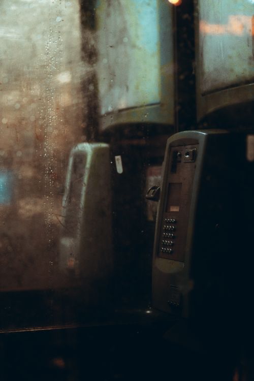 Free Moody close-up of a vintage payphone inside a weathered booth in Manchester, England. Stock Photo
