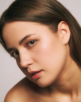 Artistic studio portrait of a woman with brown hair and a neutral expression.